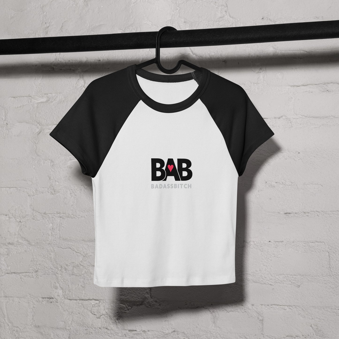 BAB Badass raglan baby tee in black and white with red heart graphic – on coat hanger view