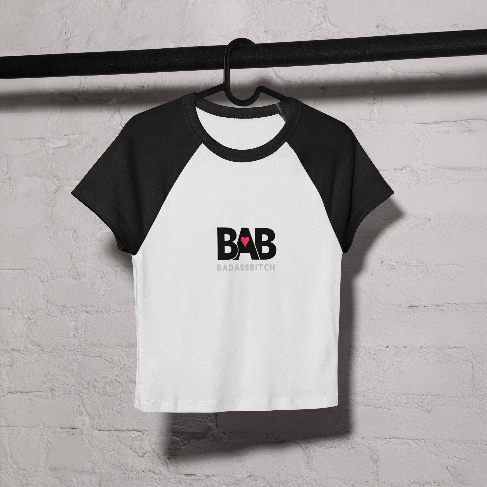 BAB Badass raglan baby tee in black and white with red heart graphic – on coat hanger view